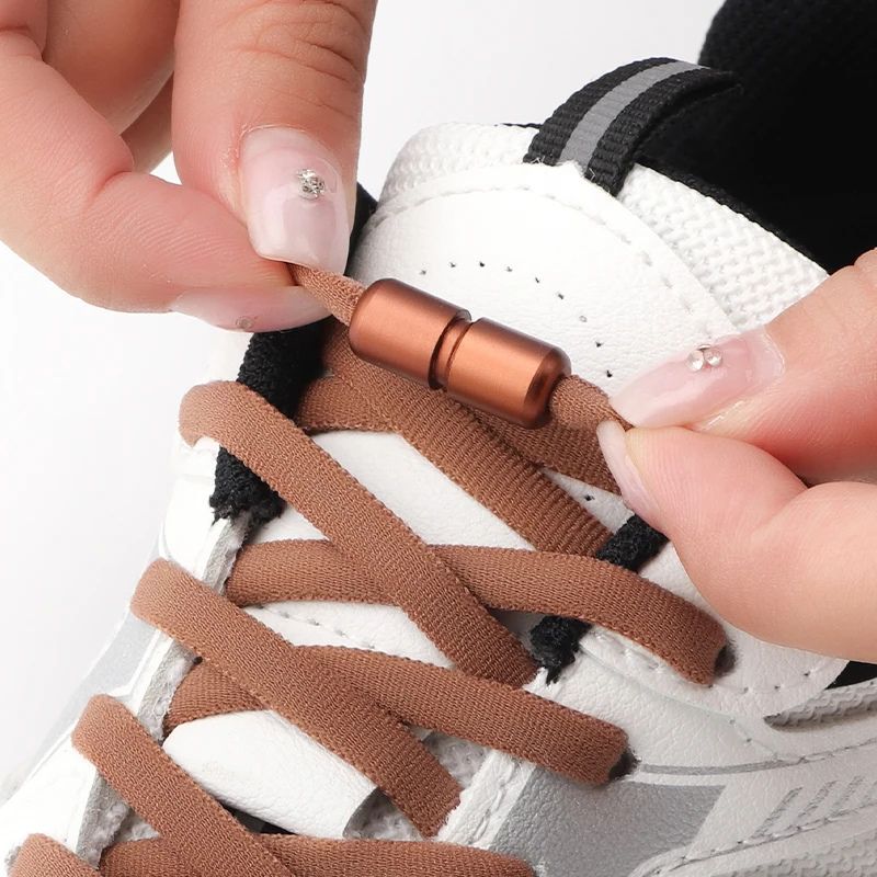 bruine compacte elastische veters zonder strikken met draaicapsule sluiting, getoond op schoen