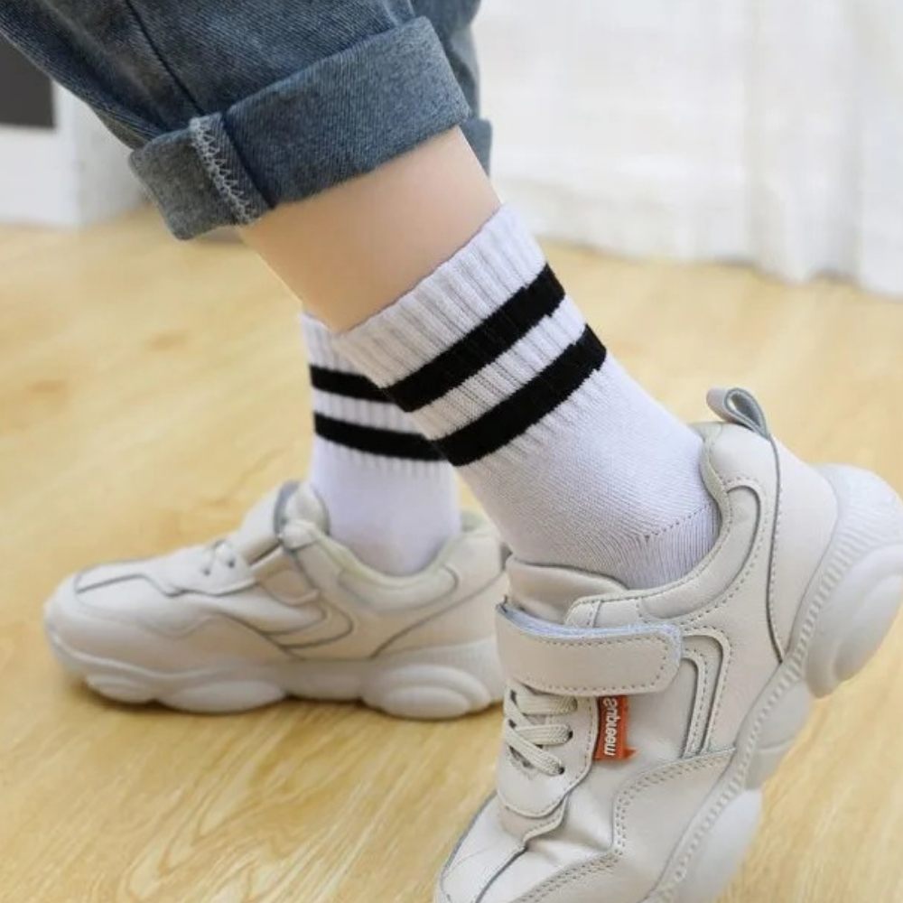 Kindervoeten in sneakers en witte dikke kindersokken met strepen van de zijkant