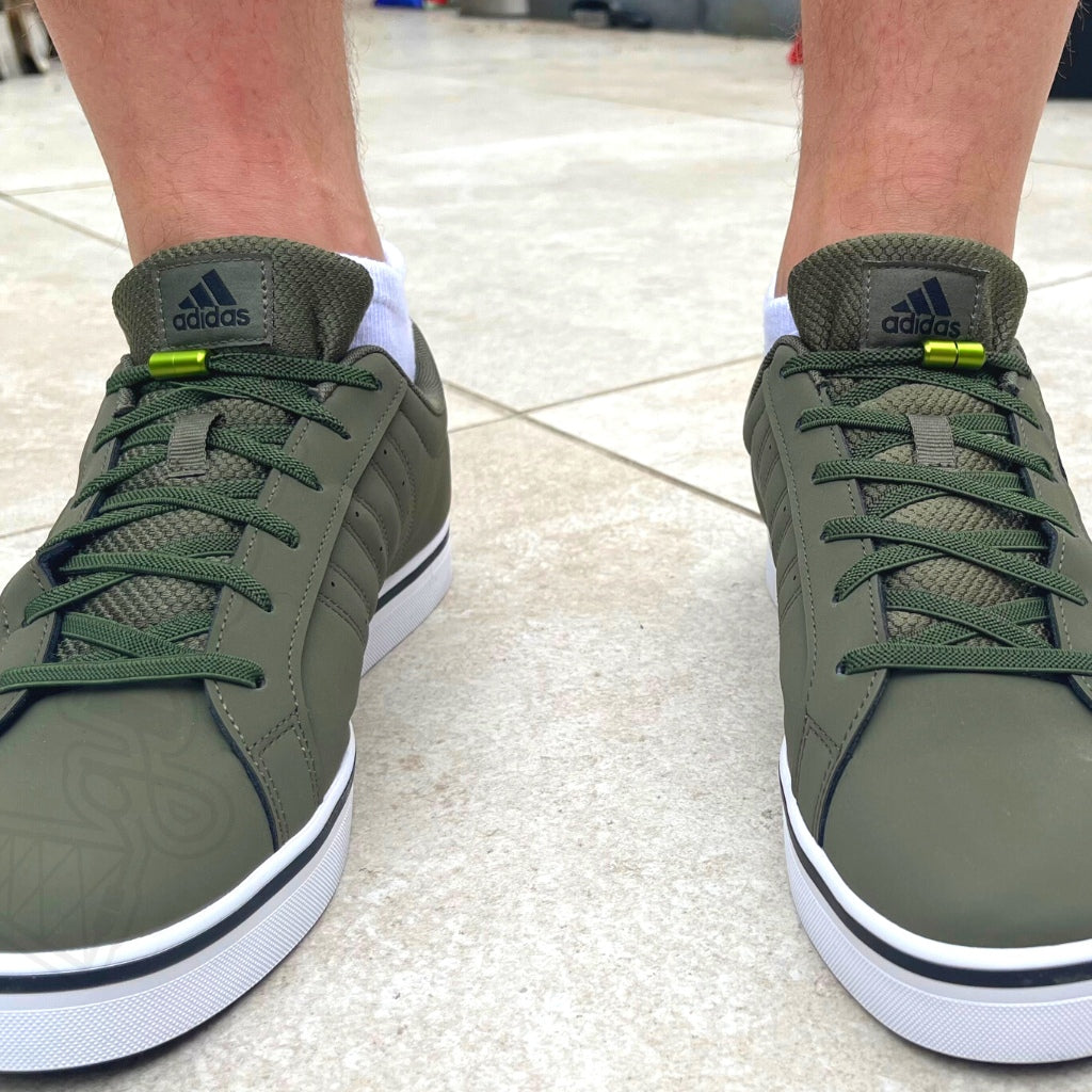 Vooraanzicht van mosgroene Adidas-schoenen met bijpassende 6mm platte elastische veters zonder strikken van Agletless®, voorzien van een draaicapsulesluiting