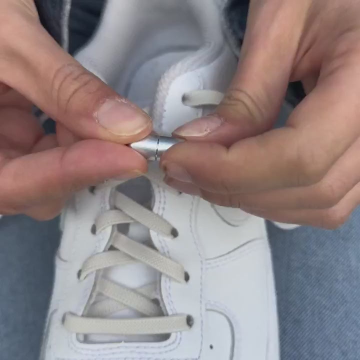 Instructievideo waarin wordt getoond hoe je stap voor stap de beige platte elastische veters van 6 mm met capsule-sluiting kunt bevestigen, inclusief het correct vastzetten van de uiteinden voor een nette afwerking